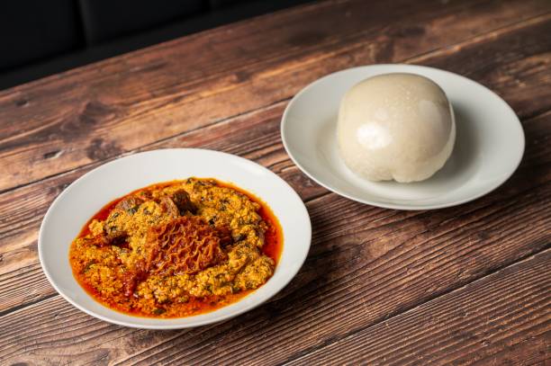 A plate of Nigerian Egusi soup served with pounded yam on a wooden table.